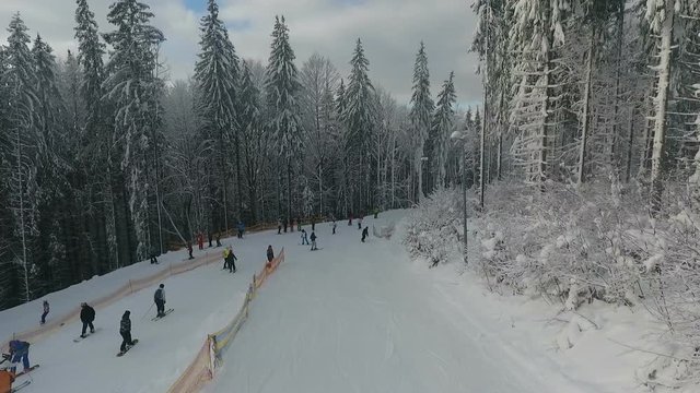Skiers and snowboarders ride on a ski slope in a mountain resort against the background of a snowy winter
