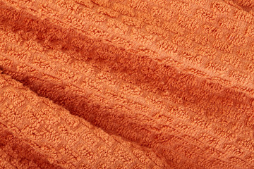 Fototapeta na wymiar orange fabric and texture concept - close up of a towel terry cloth or terry textile background