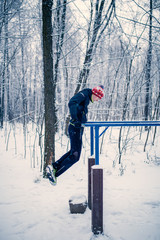 Image of sports man on horizontal bar in winter at woods