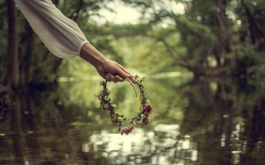 Hand of a woman holding a crown of flowers in her hand. Forest area in Frankfurt am Main, Germany. 