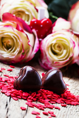 Sweet chocolate hearts, Valentines day composition with red roses, vintage wooden background, selective focus
