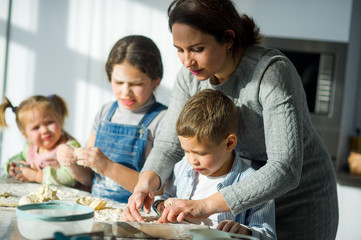 Mother teaches her children how to cook.