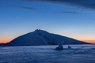 The peak of the Snezka Mountain in winter in the Krkonose Mountains. Winter landscape on the ridges in Krkonose, in front of sunrise, beautifully painted in shades of blue color. Travel concept.