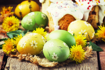 Obraz na płótnie Canvas Easter yellow and green eggs with spring dandelions, festive composition in rustic style, vintage wooden background, selective focus