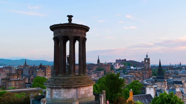 Edinburgh, UK. Calton Hill in Edinburgh, Scotland. Aerial view of the city with Castle and Clock Tower. Time-lapse pan from day to night, cloudy sky. Illuminated buildings