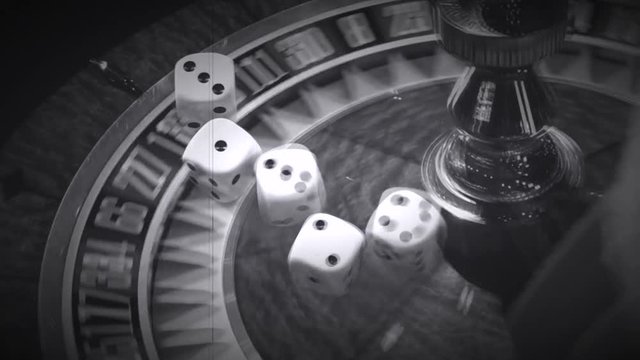 Close up of spinning roulette wheel in casino with superimposition of rolling dice and playing cards playing hands made like an old movie film in black and white