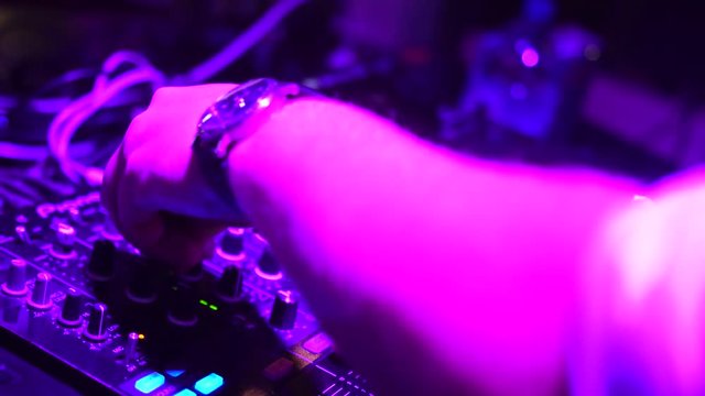 Hands of DJ tweak various track controls on dj's deck