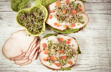 Sandwiches with lettuce, ham and broccoli sprouts.