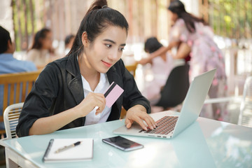 Young woman holding credit card and using laptop computer. Online shopping concept