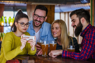 Friends in Pub drinking Beer and Looking at Smartphone