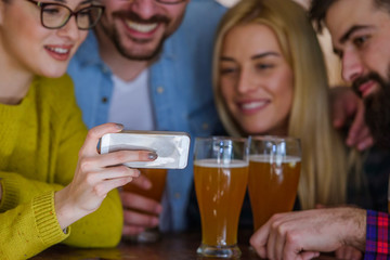 Friends in Pub drinking Beer and Looking at Smartphone