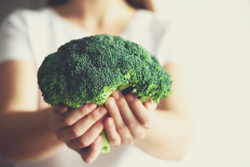 Woman in white T-shirt holding broccoli in hands. Copy space. Healthy clean detox eating concept. Vegetarian, vegan, raw concept