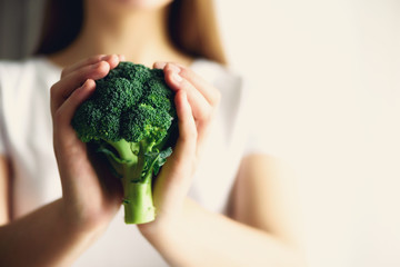 Woman in white T-shirt holding broccoli in hands. Copy space. Healthy clean detox eating concept....