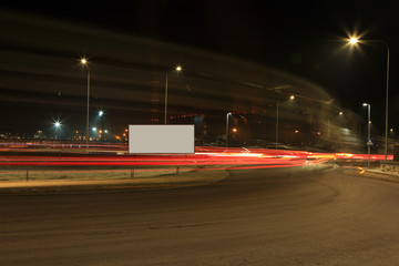 Światła samochodów nocą na drodze wokół ronda. - obrazy, fototapety, plakaty
