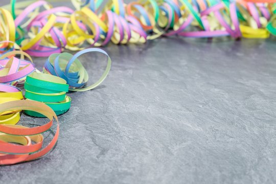 Luftschlangen als Faschingsdekoration auf einer Schieferplatte 
