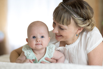 happy mother playing and hug with newborn baby in bed