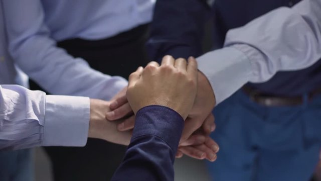 Businesspeople putting their hands on top of each other, team building support