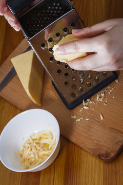 The girl is rubbing Dutch cheese on a grater