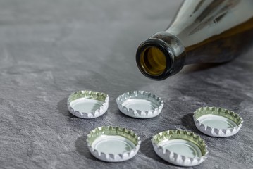 Kronkorken und eine Bierflasche auf einer Schieferplatte