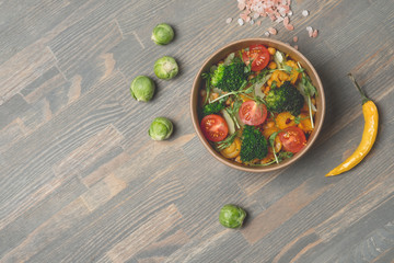 Detox vegetarian salad with mix vegetables, mix beans, pepper, dippings and fruit on wooden background.