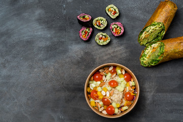 Healthy vegetarian lunch platter with veggie sushi, rice paper rolls and mix salad with beans, dippings, fruit and vegetables assorted. Flat top view, from above.