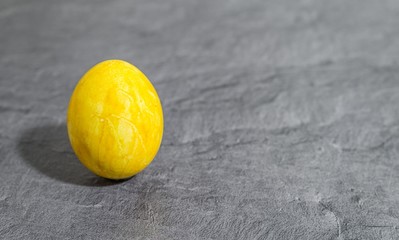 Gelbes Osterei vor grauem Hintergrund
