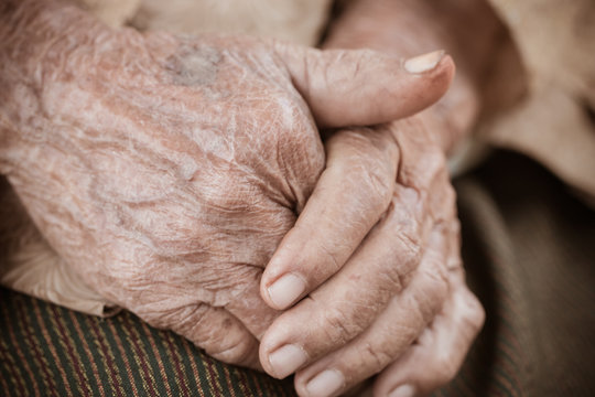 Hands Asian elderly woman grasps her hand on lap, pair of elderly wrinkled hands in prayer and Traces of hard work, World Kindness older and Adult care,  Mother day people concept
