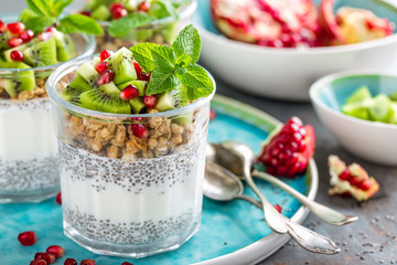 Layered chia pudding parfait with kiwi fruit, pomegranate, granola and yogurt, healthy breakfast