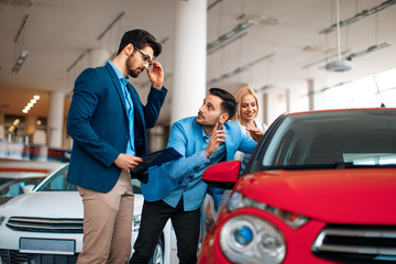 Fototapeta na wymiar Young couple choosing new car for buying in dealership shop
