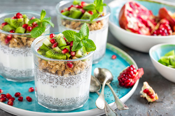Layered chia pudding parfait with kiwi fruit, pomegranate, granola and yogurt, healthy breakfast
