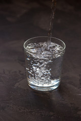 Water pouring into a glass, dark background