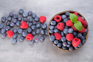 Juicy and fresh blueberries with green mint on rustic gray table.