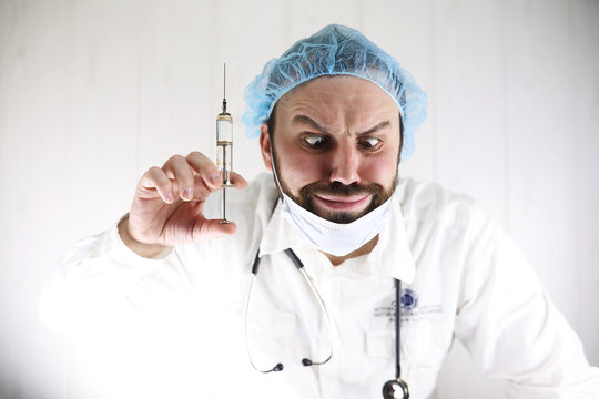 Crazy bearded doctor in a white coat and old syringe