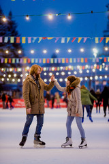 Theme ice skating rink and loving couple. meeting young, stylish people ride by hand in crowd on...