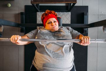 Fat sweaty woman, workout with barbell in gym