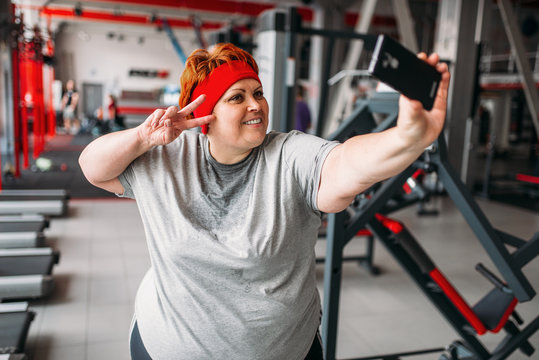 Fat woman makes selfie against exercise machines