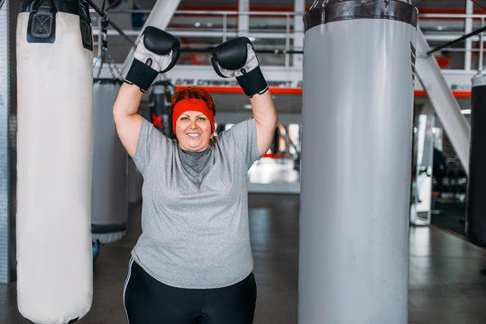 Overweight woman against punching bag in gym