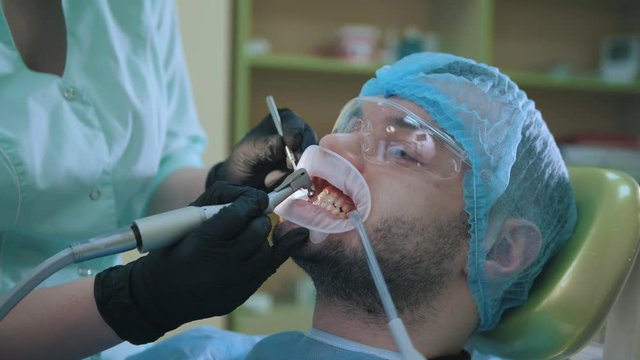 Doctor and patient with lip dilator in the dental office, polishing with stomatological brush