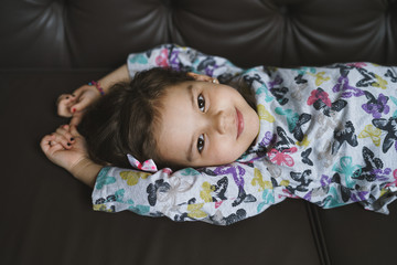 Portrait of a cute preschool girl lying and posing on the sofa
