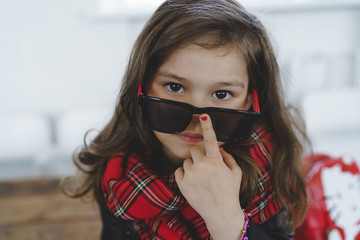 Stylish little girl sitting and fixing her shades