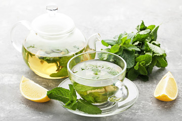 Cup of tea with mint leafs and lemons on wooden table