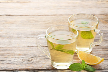 Cup of tea with mint leafs and lemon on wooden table