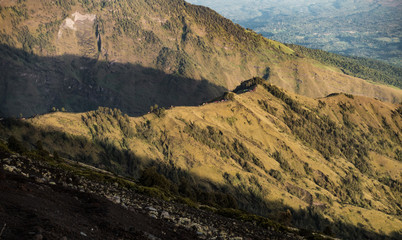the sharp of the mountain fill with the trees and the small trekking camp in the sunrise. Rinjani, Indonesia