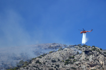 Fire helicopter extinguishes the fire on the hillside . Greece. The end of the summer.