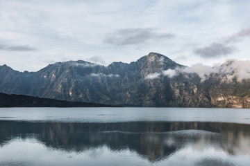 a reflective crater lake is reflecting the mountain peak around them. Rinjani, indonesia
