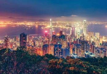 Fototapeta premium Sceniczny widok nad Hong Kong wyspą, Chiny nocą. Wielokolorowa nocna linia horyzontu z oświetlonymi wieżowcami widzianymi z Victoria Peak