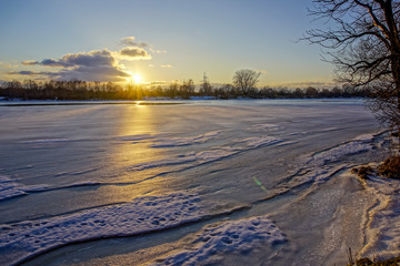 colorful winter sunset on frozen river ice