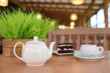 Kettle with a drink and dessert in a street cafe. Tea in the ket