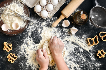Fototapeta na wymiar Woman's hands knead dough on table with flour, eggs and ingredients. Top view.