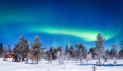 Aurora Borealis over winter wonderland scenery in Scandinavia